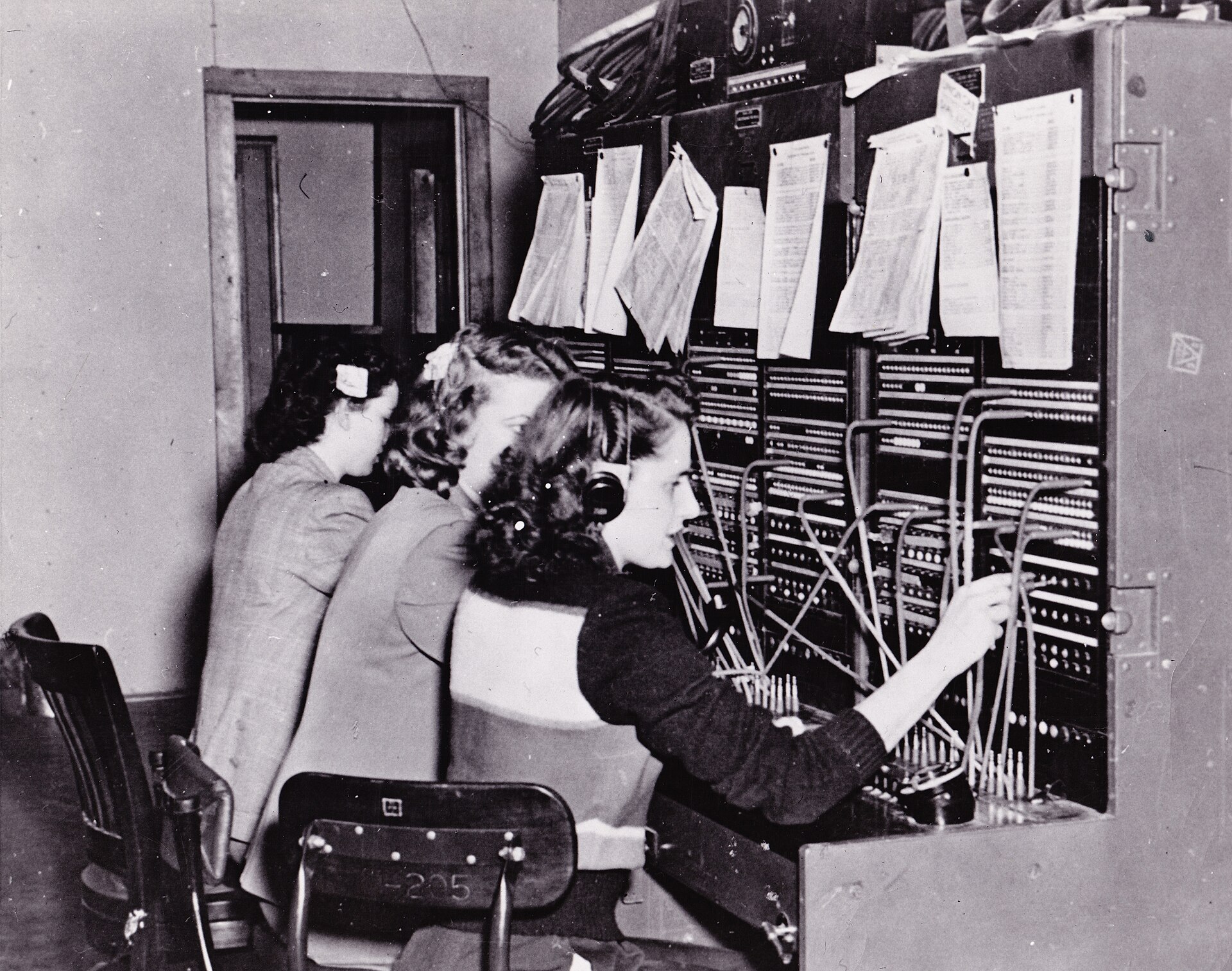 Call records clipped in sheaves along the top of a switchboard at Fort Richardson, Alaska, in 1950, above an operator's cords.